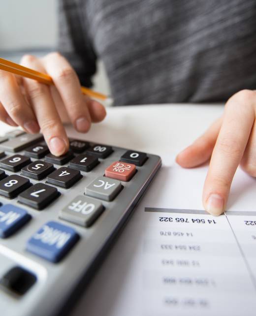 Closeup of accountant counting on calculator and working with table